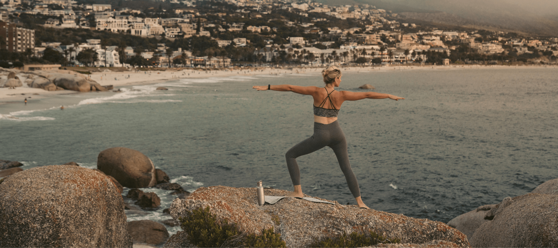 Person practicing yoga on a cliff overlooking the ocean, representing a healthy and active lifestyle for ambassadors of BioFusion Peptides