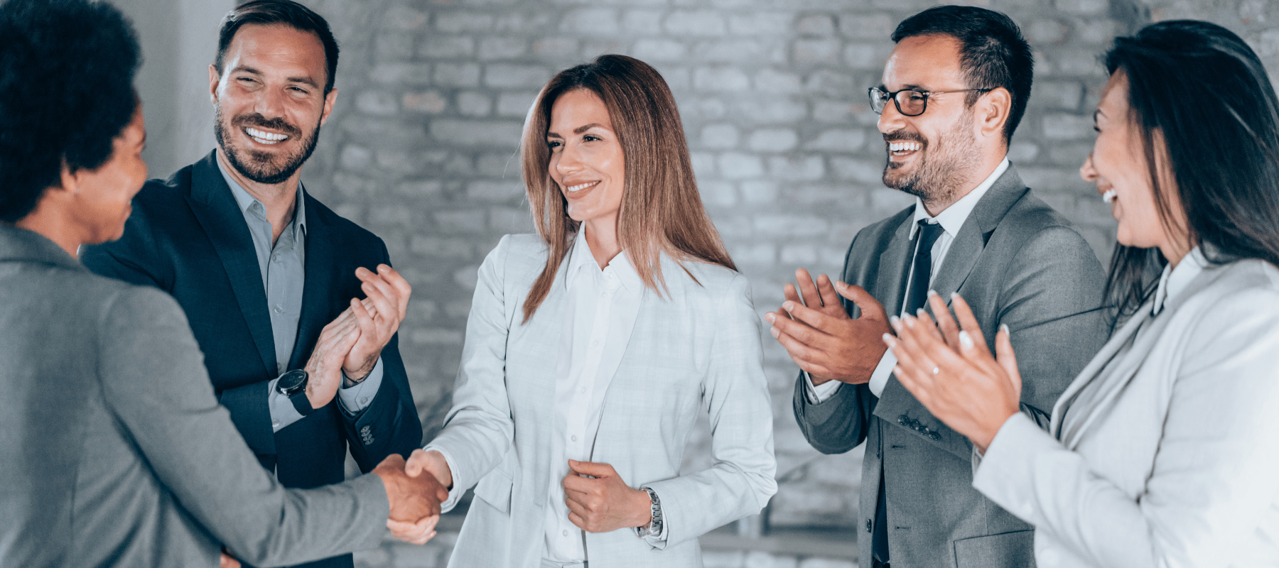 Business professionals shaking hands and applauding, symbolizing successful partnerships and collaboration