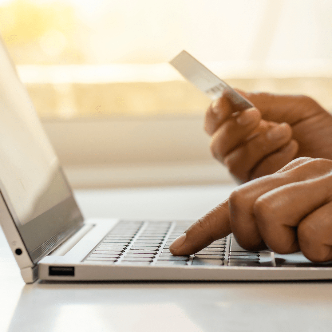 Person entering credit card information on a laptop, representing refined transactional options and secure payments