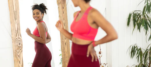 Woman smiling at her reflection in the mirror while exercising, representing effective peptide solutions for weight loss