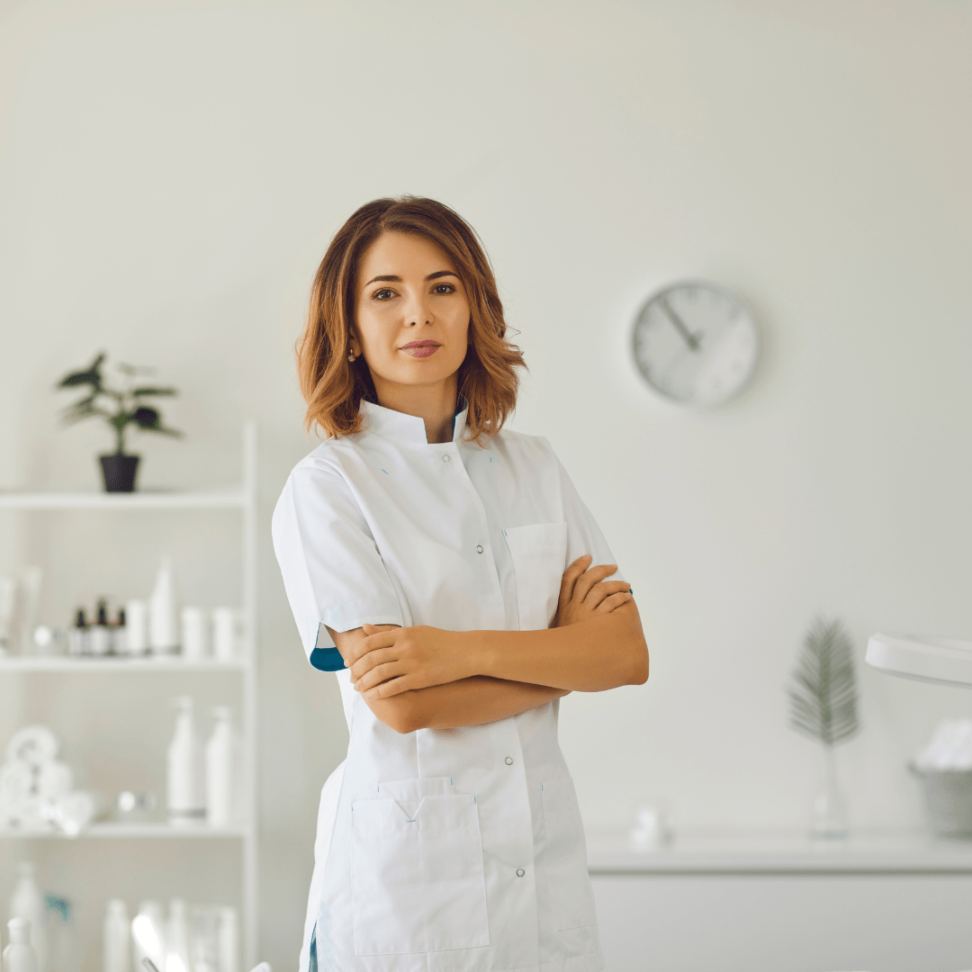 Professional woman in a lab coat standing confidently with arms crossed in a clinical setting